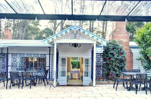 a patio with chairs and tables and an open door at Memory Lane Accommodation in Mount Tamborine