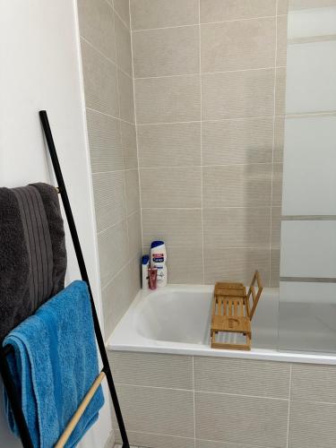 La salle de bains est pourvue d'une baignoire et d'une serviette bleue. dans l'établissement Logement bien équipé près de Paris et stade de France avec place de stationnement, à Sannois