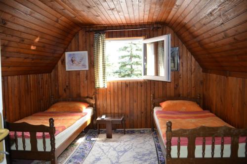 two beds in a wooden room with a window at Hondo Holiday Home in Rakovica