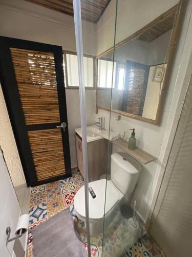 a bathroom with a toilet and a sink and a mirror at Alojamiento cerca a La Mesa con Piscina in Cachipay