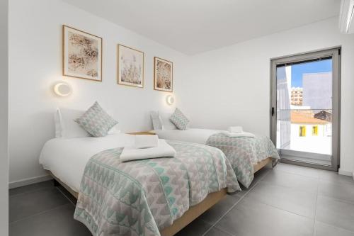 two beds in a white room with a window at Gaivota Ocean view & 5min walk beach in Luz