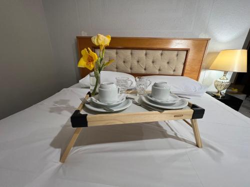 a tray with plates and cups and flowers on a bed at POUSADA BELLA CANASTRA in Piumhi
