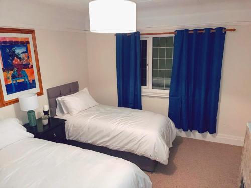 a bedroom with two beds and a window with blue curtains at Large Cottage 4BR, PARKING, NEC, AIRPORT, JAGUAR in Birmingham