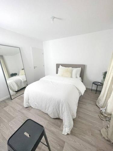 a white bedroom with a white bed and a mirror at Allée des cedres in Villepinte