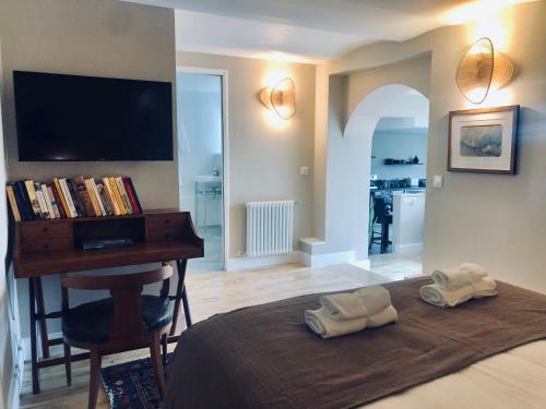 a bedroom with a bed with a desk and a television at Les Grands Jardins Lodge in Giverny