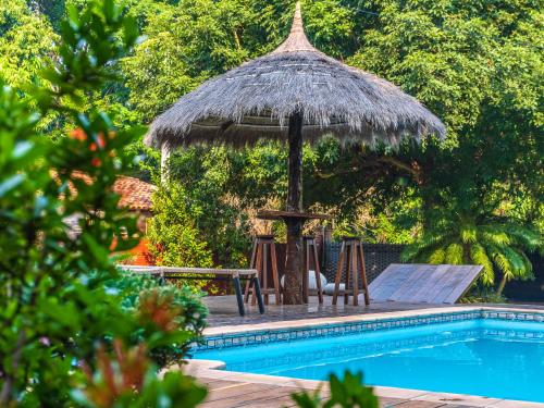 a pool with a umbrella and a table and chairs at Quinta La Paloma in Itauguá