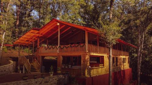 a log cabin with a deck in the woods at Cabañas Los Encinos in Acaxochitlán