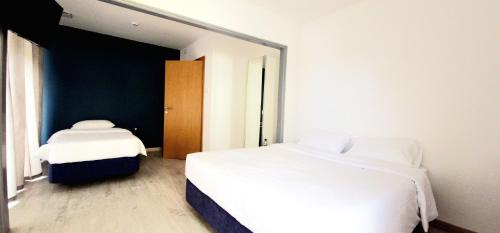 a bedroom with two white beds and a mirror at Marinha Garden Inn in Marinha Grande