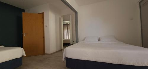 1 dormitorio con 2 camas y puerta de madera en Marinha Garden Inn en Marinha Grande