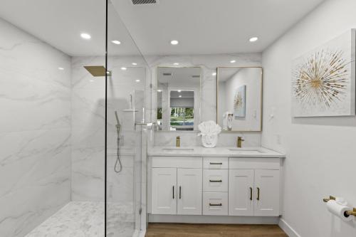 La salle de bains blanche est pourvue d'une douche et d'un lavabo. dans l'établissement Tropical Haven in Ft. Myers, à Fort Myers