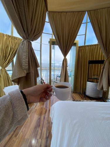 a person holding a bowl of coffee in a bedroom at Guatavita Glamping club in Bogotá
