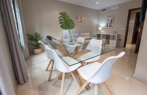 comedor con mesa de cristal y sillas blancas en Apartamento céntrico Rincón de Ensueño parking gratis, en Jaén