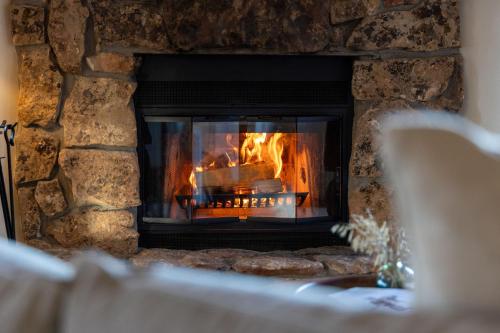 a stone fireplace with a fire in it at Pine Perch ~ Cozy Mountain Cabin w/ Views in Bailey