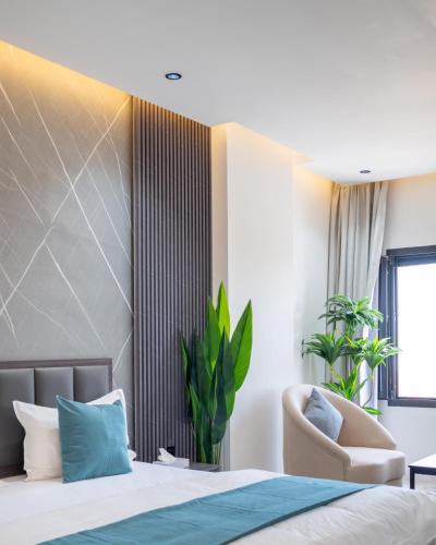 a bedroom with a bed and a chair at جوهرة مسقط للشقق الفندقية in Ma‘ābīlah