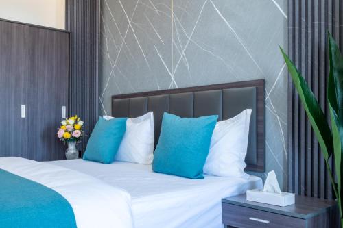 a bedroom with a bed with blue pillows at جوهرة مسقط للشقق الفندقية in Ma‘ābīlah