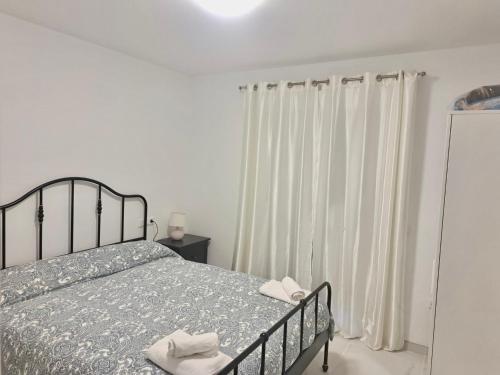 een slaapkamer met een bed en een raam met witte gordijnen bij Apartamento El Primer Sol in Nerja