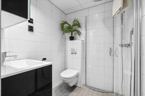 a bathroom with a toilet and a sink and a plant at Studioleilighet, uten soverom in Bodø