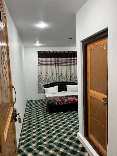 Schlafzimmer mit einem Bett, einem Fenster und einer Tür in der Unterkunft THE ALPINE KARGIL Guest House in Kargil