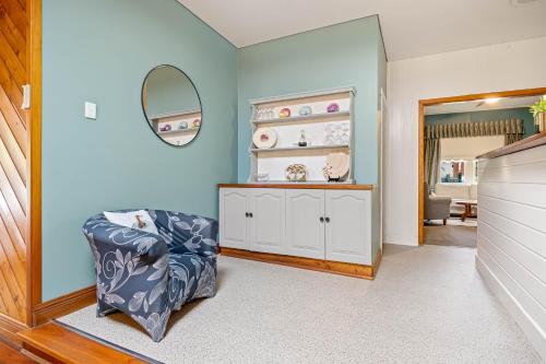 Habitación azul con silla y espejo en Ballarat Cottages en Ballarat