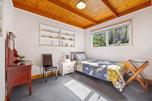 a bedroom with a bed and a desk and a window at Ballarat Cottages in Ballarat