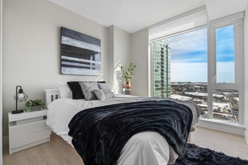 a bedroom with a bed and a large window at NEW! Tranquil Vibes & Downtown Views, Near Stampede & Saddledome, FREE Parking, Banff Pass, Wine & Gym! in Calgary