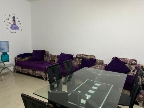 a living room with purple couches and a glass table at Seaside master bedroom in Sharjah
