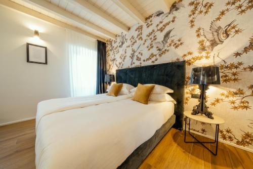 ein Schlafzimmer mit einem großen weißen Bett in einem Zimmer in der Unterkunft Il Vicolo Suite Apartments - Il Corso in Tignale