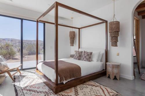 1 dormitorio con cama con dosel en una habitación con ventanas en Moroccan Swim House- Joshua Tree Mia Riad, en Yucca Valley
