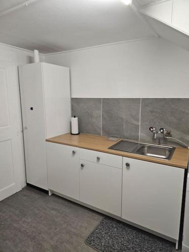 una cocina con armarios blancos y fregadero en L'appart - Couvet, en Couvet