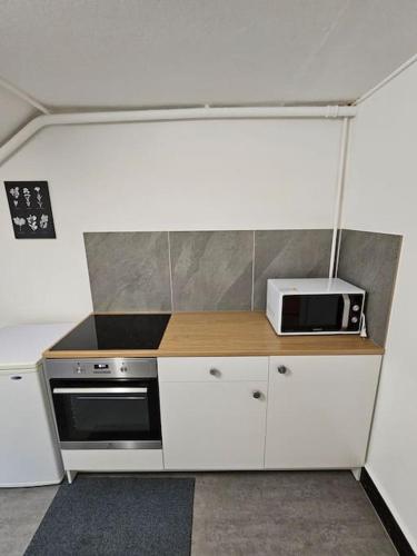 a small kitchen with a stove and a microwave at L'appart - Couvet in Couvet