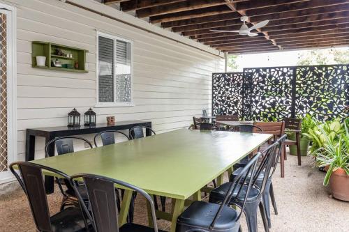 a green table and chairs on a patio at BirdSong Yeronga - Inner City Village Sanctuary in Brisbane