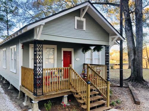 una casa pequeña con porche y puerta roja en Spacious Waterfront Cottage + 2.5 Acres on the Bay en Lafayette