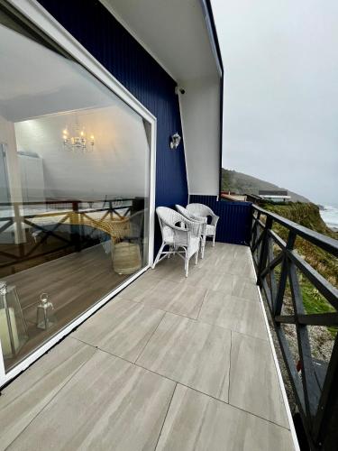 a balcony of a house with a table and chairs at Curiñanco Casa Playa in Curiñanco