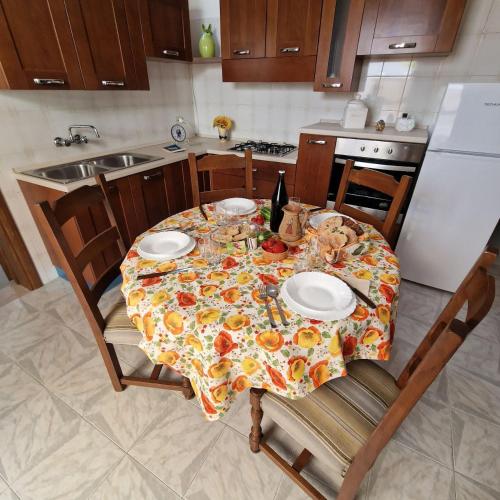 a kitchen with a table with plates and a bottle of wine at Casa Marcel in Ugento