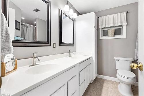 Un baño blanco con lavabo e inodoro. en Tropical Breeze Canal Waterfront Home, Heated Pool, en Cabo Coral