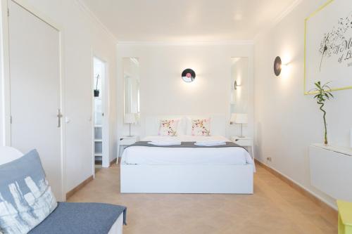 a white bedroom with a bed and a chair at Vinyl Flat Bed & Breakfast - Rooms in Lagos