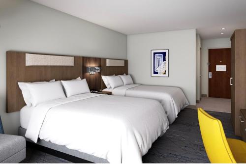 two beds in a hotel room with a yellow chair at Holiday Inn Express Suites Little Rock West, an IHG Hotel in Little Rock