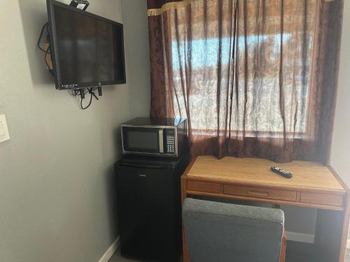 a room with a desk with a microwave and a television at super inn in Newport