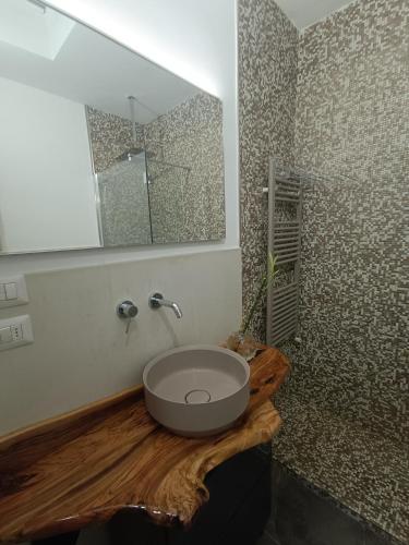 a bathroom with a sink on a wooden counter with a mirror at RESIDENCE TERRAE Intero appartamento 2 CAMERE MATRIMONIALI in San Ligorio