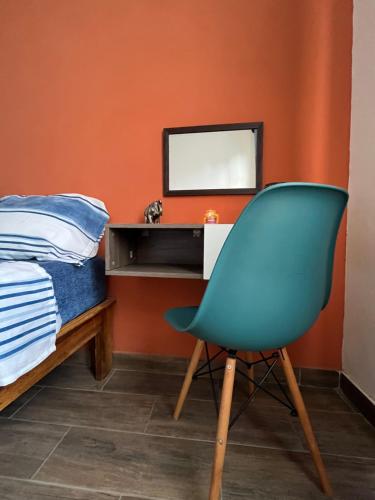 um quarto com uma cama, uma cadeira e uma televisão em Casa Tezcal em Oaxaca de Juárez