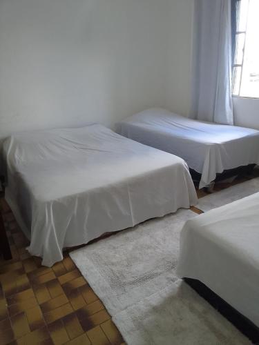 two beds with white sheets in a room at LINDO APTO CENTRAL, MOBILIADO, AO LADO DO HOTEL NACIONAL CORUMBÁ -MS in Corumbá