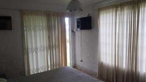 a bedroom with a bed and a window with curtains at Holiday Flat at Vaaldam Sgt Pepper's in Oranjeville
