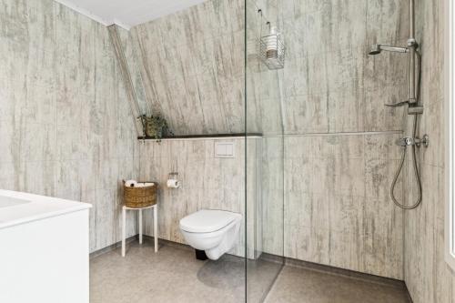 a bathroom with a toilet and a glass shower at Romslig 3-soveroms toppleilighet midt i sentrum in Egersund