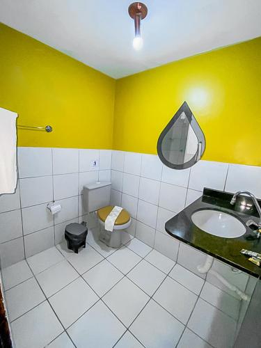 a bathroom with a sink and a yellow wall at Pousada Flat Castor in Natal