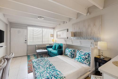a small bedroom with a bed and a blue chair at Fontainebleau Terrace 223 in Panama City Beach