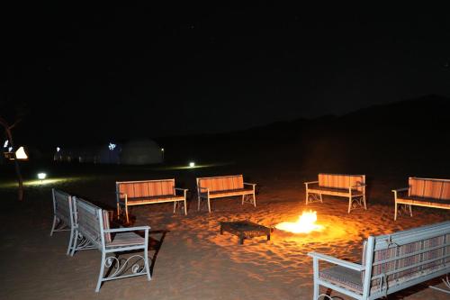 a group of chairs around a fire in the sand at night at Luxury Desert Camp Oman in Al Wāşil