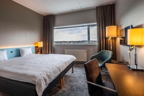 コペンハーゲンにあるスカンディック スルーシュホルメンのベッド、デスク、窓が備わるホテルルームです。
