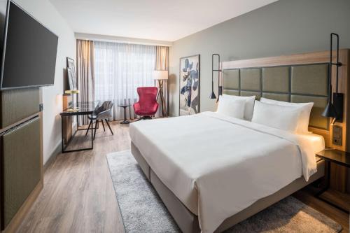 a hotel room with a large bed and a red chair at Radisson Blu Hotel, Hamburg Airport in Hamburg