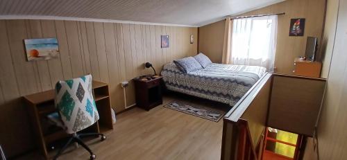 Habitación pequeña con cama y escritorio. en Cabañas Los Geranios en Osorno