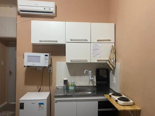 a small kitchen with a sink and a microwave at Flat à beira mar! in Marechal Deodoro